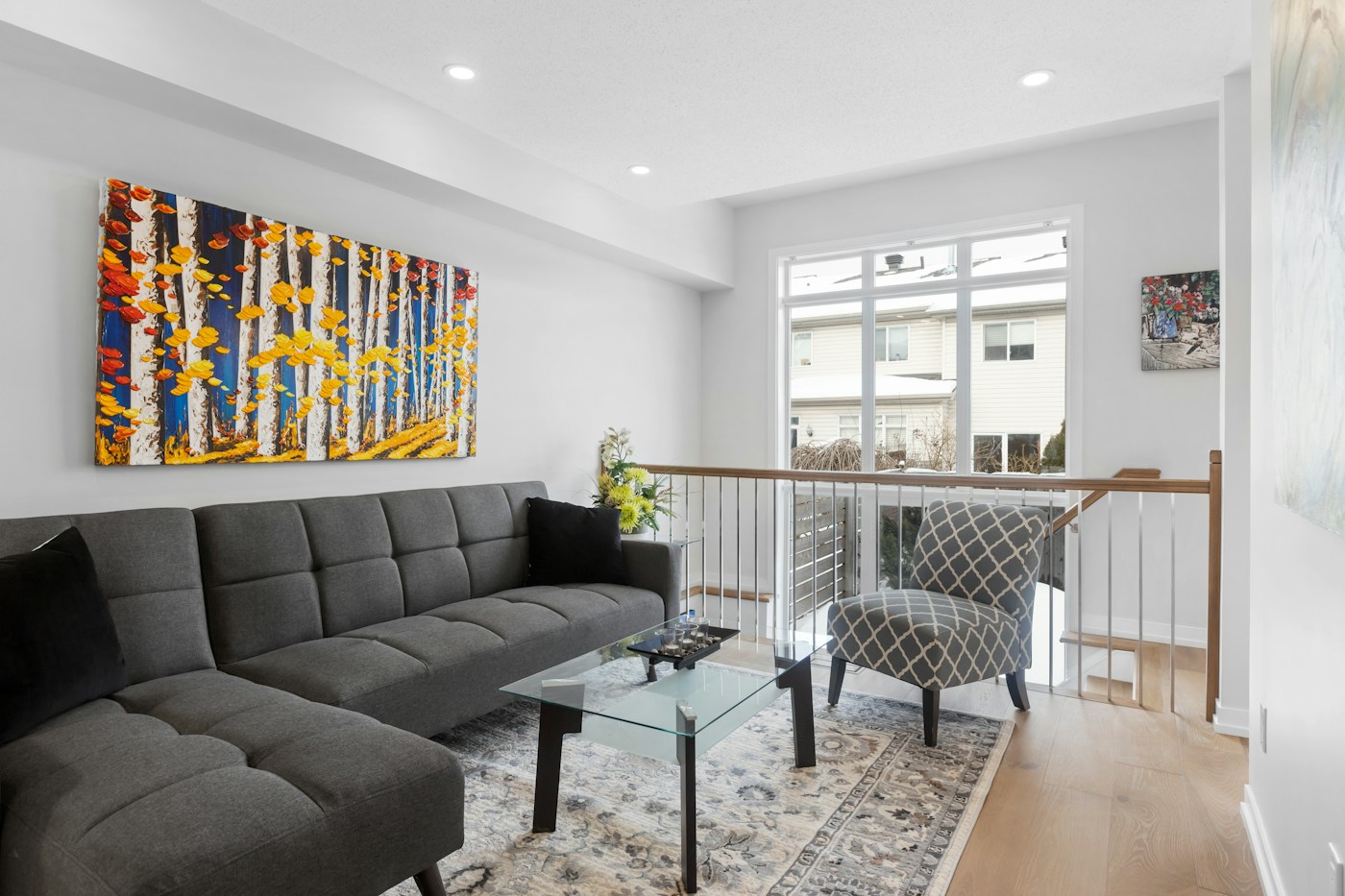 A bright living room with a grey sofa, fresh walls and a colourful painting